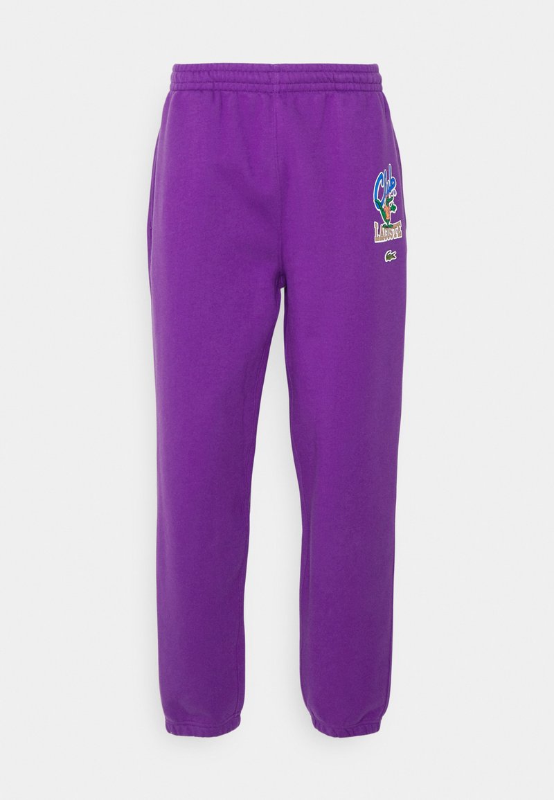 Lila Jogginghose mit einem elastischen Bund, ausgestattet mit Seitentaschen und gestickten Logos in kontrastierenden Farben auf dem oberen linken Bein.