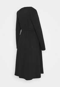 Vestido negro de manga larga hecho de una tela suave, con una cintura ajustada y un dobladillo acampanado, con un sutil detalle en la parte posterior.