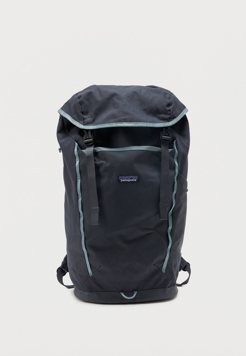 Σκούρο μπλε σκούρο σακίδιο πλάτης Patagonia με επάνω καπάκι, δύο μπροστινές λουρίδες, γαλάζιο περίγραμμα και μικρό μπροστινό λογότυπο, εμφανίζεται σε απλό λευκό φόντο.