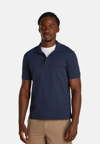 Camisa polo de color azul marino con mangas cortas, cuello tipo polo y botones. Fabricada en tela suave, con un diseño ajustado.