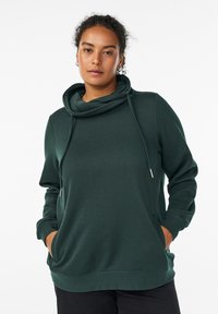 Felpa verde a maniche lunghe con collo a imbuto e cordini regolabili. Realizzata in un materiale morbido e testurizzato, presenta tasche anteriori.