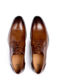 Chaussures habillées en cuir marron avec une finition lisse, bout rond, lacets et détails de couture subtils. L'intérieur est doublé de cuir beige.