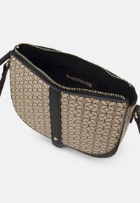 Borsa a tracolla beige e nera con motivo e chiusura con zip, caratterizzata da un bordo in pelle liscia, hardware dorato e un'etichetta interna.