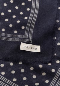 Tissu bleu marine à pois blancs avec bordure rayée, avec une étiquette blanche à texte noir indiquant "PART TWO."