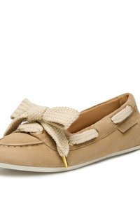 Mocassino in suede beige con un grande fiocco intrecciato, dettagli in hardware dorato e una suola in gomma bianca. Dettagli di superficie testurizzati.