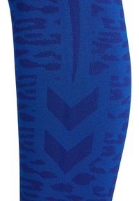 Niebieska dzianina z ciemniejszymi niebieskimi wzorami w jodełkę i abstrakcyjnymi motywami lamparta tkanymi w tkaninę.