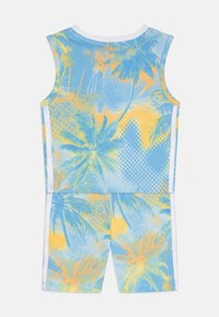 Blå och gul tvådelad outfit bestående av en linne och shorts. Designen inkluderar palmträd och geometriska mönster med en texturerad finish.