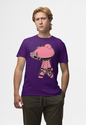 Ung mand med lyst hår iført en lilla t-shirt med en lyserød tegneserie-bjørn i sorte læderremme og en mundkurv.