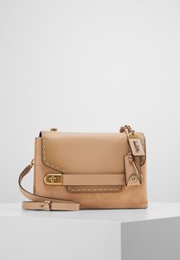 Borsa a tracolla in pelle beige con cuciture a contrasto, chiusura a patta, tracolla regolabile e dettagli in hardware dorato. Texture morbida con una forma strutturata.