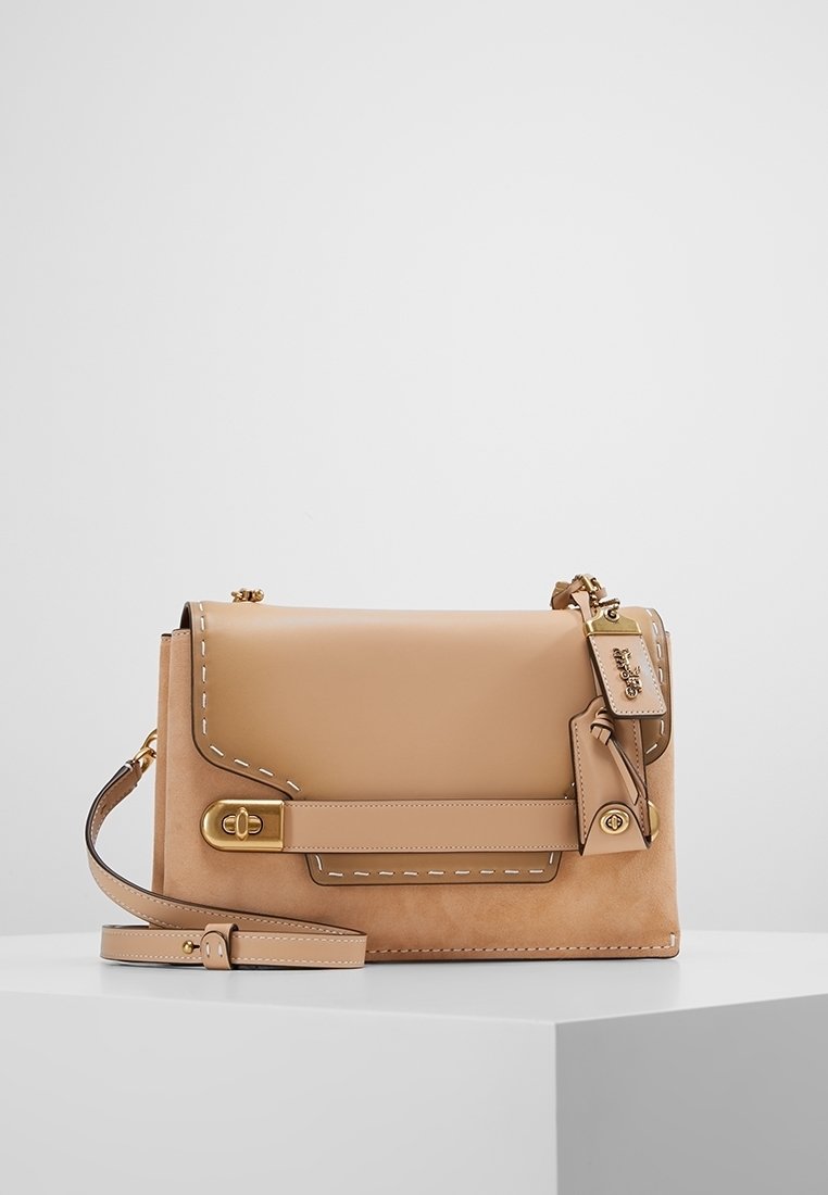 Borsa a tracolla in pelle beige con cuciture a contrasto, chiusura a patta, tracolla regolabile e dettagli in hardware dorato. Texture morbida con una forma strutturata.