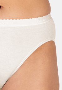 Slip in cotone bianco con una texture morbida, dotato di una vita scallopata e di un branding sottile. Il design presenta un taglio classico.