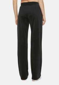 Pantaloni a gamba larga in velluto nero con una texture morbida, dotati di una vita elastica e un design minimalista. Nessun motivo o accentuazione visibile.