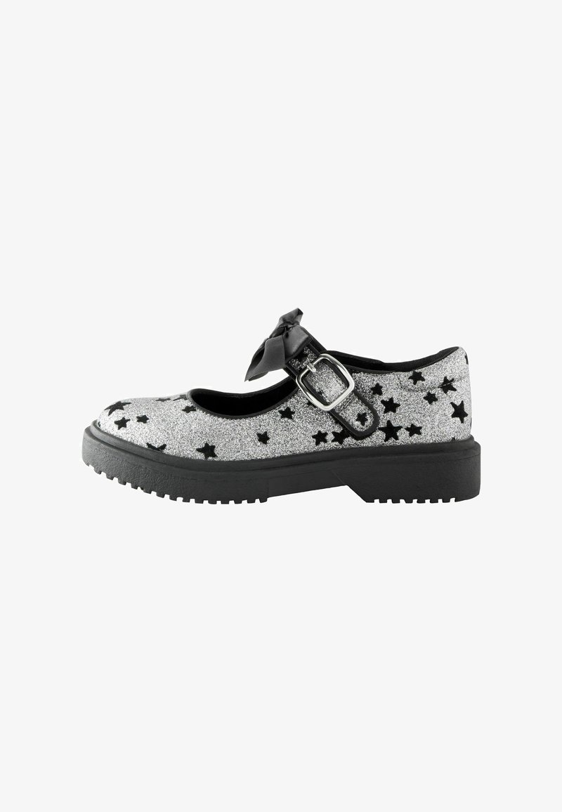 Silver glitter Mary Jane shoe with black star patterns, thick black sole, adjustable buckle strap, and decorative black bow.