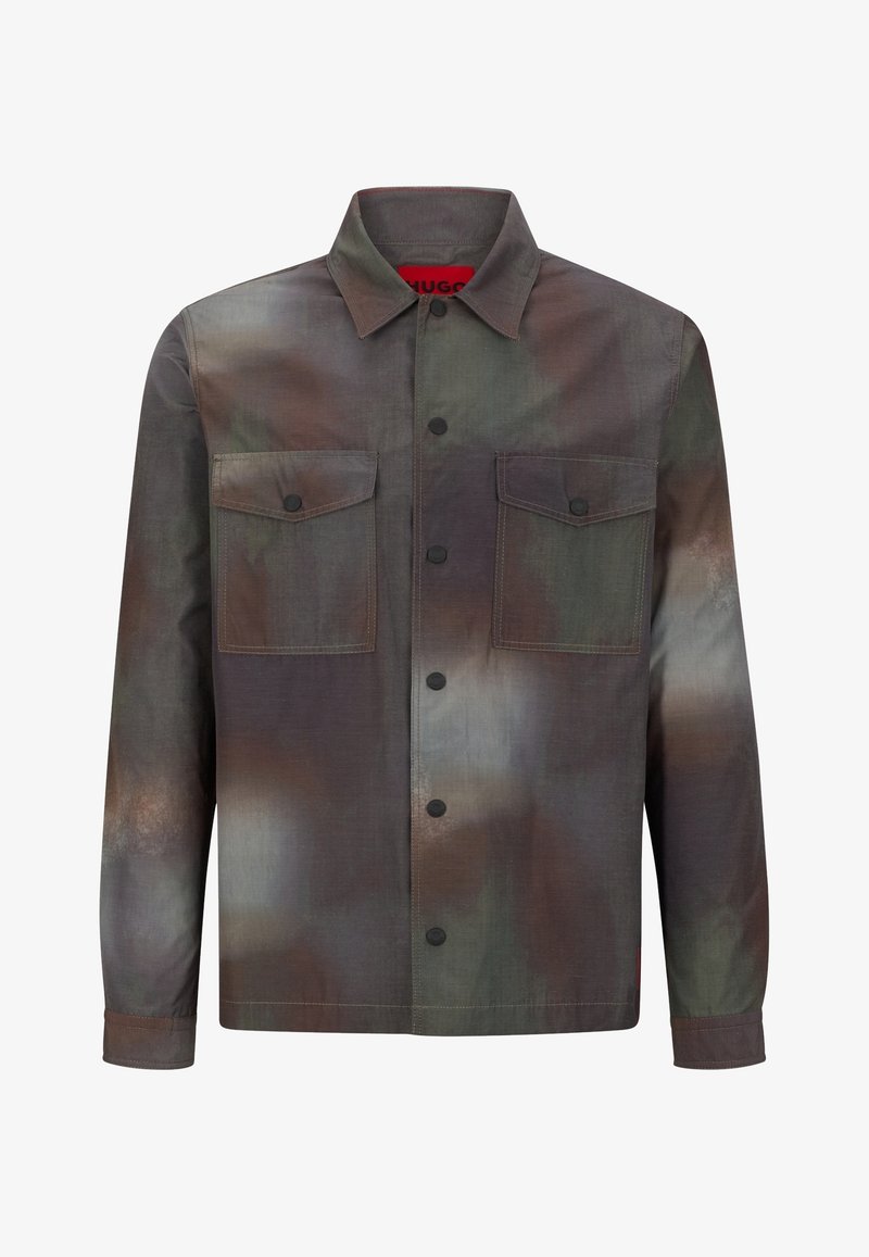 Camisa chaqueta de manga larga con patrón de camuflaje en verde, marrón y gris y dos bolsillos delanteros con solapa y botones negros.