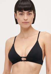 Zwarte driehoek bikini-top van soepel materiaal met dunne verstelbare bandjes en een uitgesneden ontwerp met een klein logo-accent.
