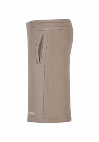 Lys brun tanktopp med en jevn tekstur, med en sidelomme og ribbet halslinning. Enkelt design med en logo aksent nær kanten.