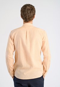 Perzikkleurig overhemd met lange mouwen van een textuurstof, voorzien van een button-down kraag, een rugplooien en knoopsluiting bij de mouwen.