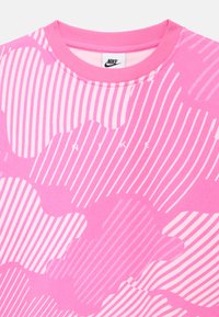 Ροζ φούτερ Nike με κυματιστό ριγωτό μοτίβο. Διαθέτει λαιμόκοψη και απαλό ύφασμα. Λογότυπο "NIKE" σε λευκό στο κέντρο.