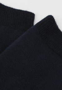 Mørkeblå sokker med en blød, tekstureret overflade. Har en ribbet manchet øverst, der giver elasticitet og komfort.