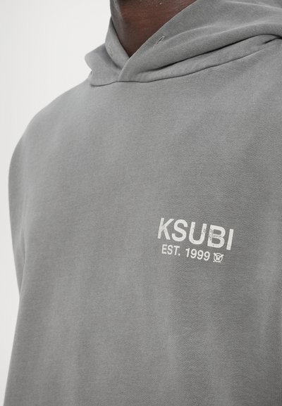 Gray hoodie made of soft fabric, featuring a large front pocket, adjustable drawstring hood, and a white Ksubi logo with "EST. 1999" detail.