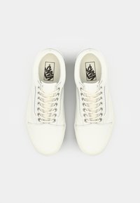 White canvas sneakers with rounded toes, flat laces, and a logo on the tongue. Features subtle stitching and a textured rubber sole.