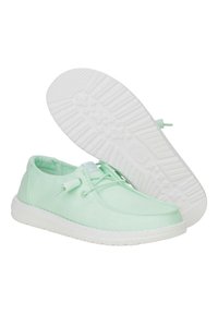 Scarpe in tela verde menta con suola in gomma bianca, caratterizzate da un design con lacci e suola testurizzata con stelle. Superficie liscia e forma arrotondata.