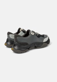 Gray and black sneakers with a chunky sole, suede and synthetic upper, contrasting textures, and lace-up design. Vibram branding on the sole.