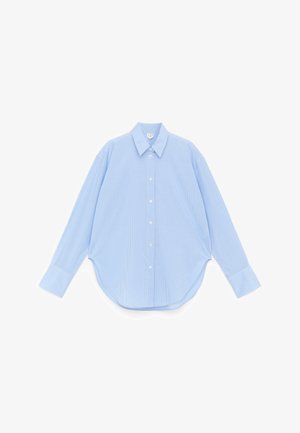 Chemise bleu clair à manches longues avec petit motif à carreaux, col pointu et ourlet arrondi, posée à plat sur fond blanc.