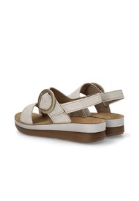 Sandalias de cuero beige con una correa ancha y un detalle de herraje circular. Cuenta con una plantilla texturizada y una suela blanca contrastante con una base marrón.
