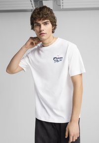 Biała koszulka z bawełny z kolorowym logo Puma na piersi. Koszulka ma klasyczny okrągły dekolt i krótkie rękawy.