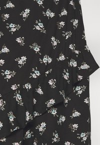 Musta kangas, jossa on pieniä, pastellinvärisiä kukka-ompeluja. Siinä on röyhelöhelma ja herkät lehdet yksityiskohtina. Pehmeä rakenne.