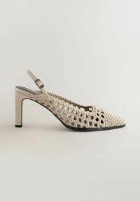 Escarpin slingback en cuir tressé beige avec un bout pointu et un talon bloc de hauteur moyenne sur un fond neutre.