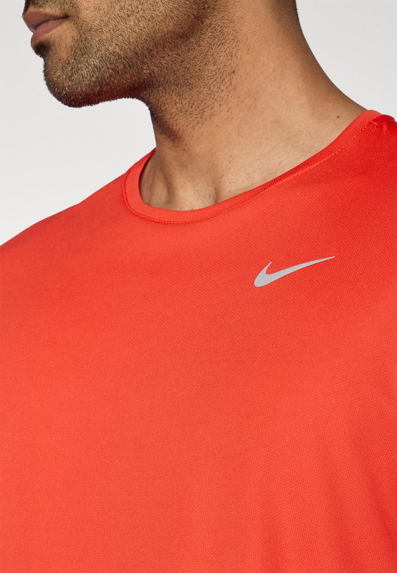 Rotes Sportshirt mit rundem Ausschnitt, aus strukturiertem Stoff, mit einem kleinen silbernen Nike-Logo oben links.
