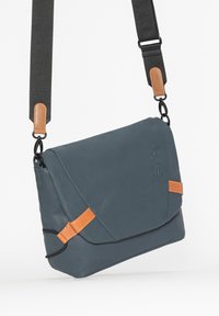 Messenger-Bag aus dunkelblauem Material mit hellbraunen Lederelementen; verfügt über einen verstellbaren grauen Riemen und einen Klappenverschluss.