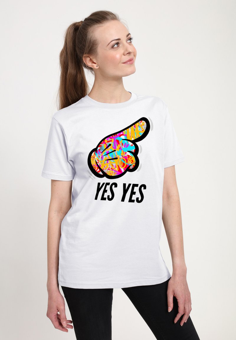 Hvid T-shirt med et farverigt grafisk design af en pegende hånd og teksten "JA JA" i fede sorte bogstaver.