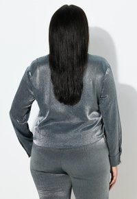 Shiny gray long-sleeve top and matching pants made of a smooth, reflective fabric. The outfit features fitted design and visible seams.