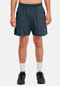 Donkergrijze sportshorts met een elastische tailleband, zijzakken en een lichte stof. Draag ze met witte sokken en zwarte sneakers.