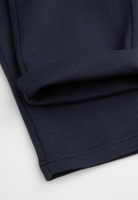 Granatowy złożony materiał charakteryzuje się gładką fakturą, czystymi szwami i subtelnym wzorem rozciągającym. Odpowiedni do odzieży domowej lub codziennego użytku.