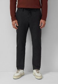 Donkere grijze broek van een zachte stof, met een taille met trekkoord en een taps toelopend ontwerp van de pijpen, gecombineerd met witte sneakers.