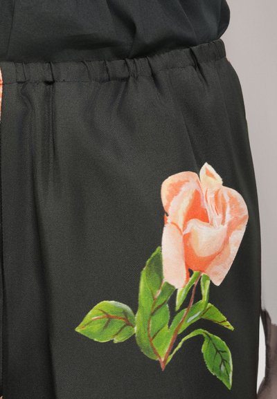 Material negru cu un timp de talie adunat, prezentând un design mare cu trandafiri roz și frunze verzi, evidențiind detaliile imprimeului floral.