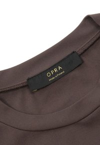 Brązowa koszulka z tkaniny z okrągłym dekoltem. Wyposażona w czarną metkę z złotym napisem "OPRA" oraz "Wyprodukowano w Polsce". Gładka faktura.