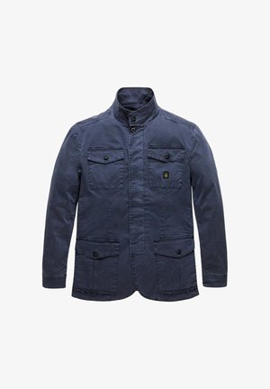 Giacca da uomo blu navy con collo alto, chiusura frontale con bottoni, quattro tasche con patta e bottoni, e una piccola toppa con logo sulla tasca del petto.