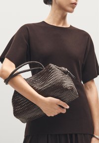 Sac en cuir tressé marron avec une finition texturée, doté de deux anses tressées et d'une fermeture éclair en haut.