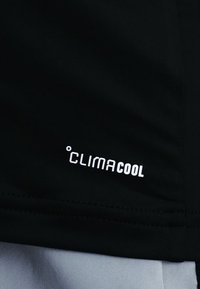 Tissu noir avec logo blanc "CLIMACOOL" imprimé près de l'ourlet, avec un petit symbole de degré avant le texte.