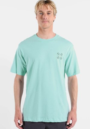 T-shirt vert menthe clair en coton, avec col rond, manches courtes et un petit motif floral sur le côté gauche de la poitrine.