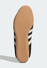 Svart atletisk skosula med texturerad beige gummi, med tre vita ränder på sidan och präglad "adidas" logotyp.