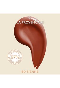 Crème marron en forme lisse et courbée avec une texture brillante, étiquetée "60 Sienne" et "97 % d'ingrédients naturels" sur fond clair.