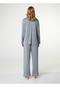 Maglietta grigia a maniche lunghe e pantaloni coordinati a gamba larga realizzati in un tessuto morbido. Il set presenta bordi bianchi sui polsini dei pantaloni. Vista posteriore mostrata.