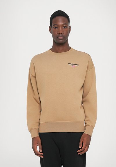Beige pamut pulóver, bordázott mandzsettákkal és aljjal. Kicsi fekete "POLO SPORT" logó és amerikai zászló grafika található a mellkason.