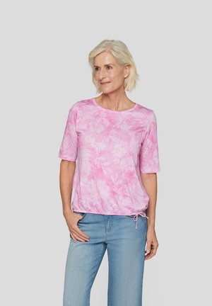 Rosa blumengemusterte Kurzarmbluse mit Rundhalsausschnitt und verstellbarem Kordelzugsaum, kombiniert mit hellblauen Jeans.